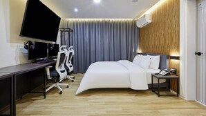 Una habitación de hotel moderna con cama, escritorio, silla, televisor y equipo de ejercicio.