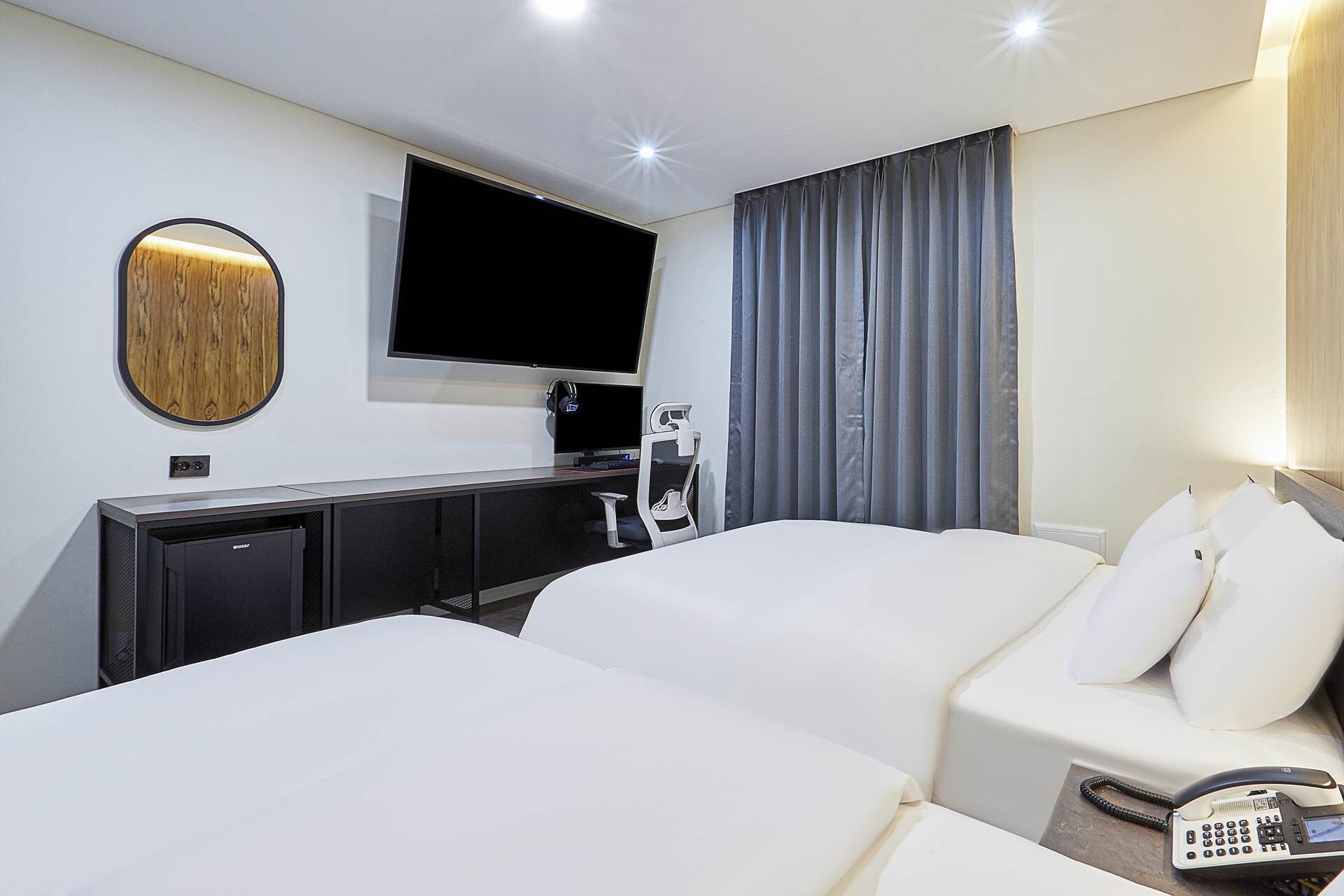 A hotel room with a bed, a desk, a television, and a telephone.