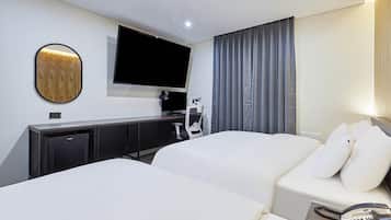 A hotel room with a bed, a desk, a television, and a telephone.