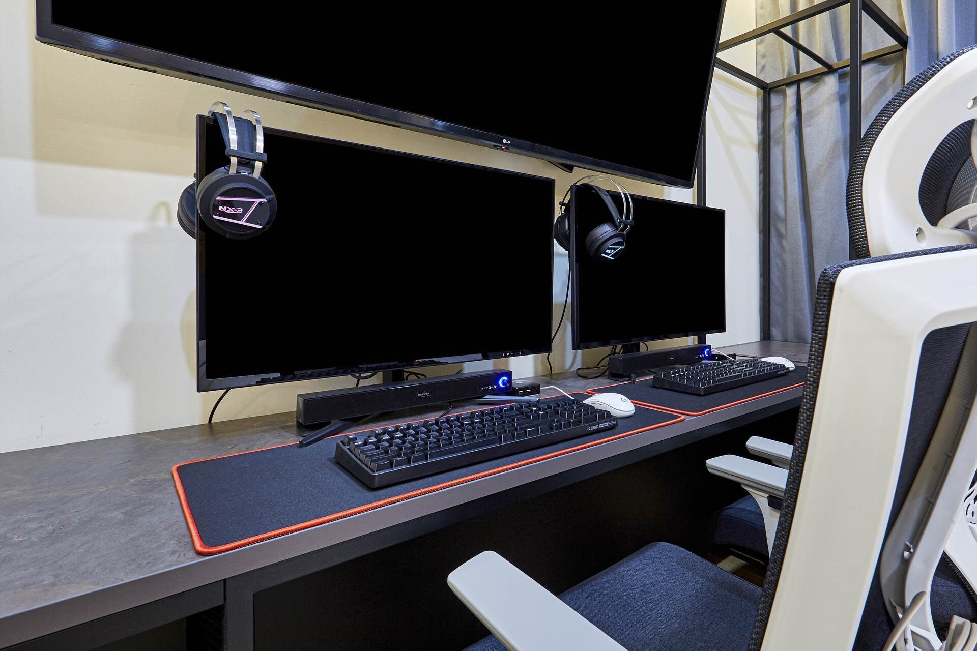 A dual-monitor setup with a keyboard and mouse, a headset, and a chair.