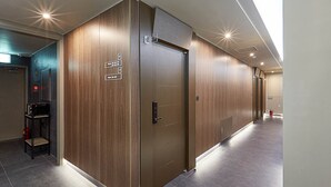 Un pasillo moderno con paneles de madera, un extintor y un ascensor.
