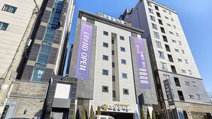 Un edificio de varios pisos con un letrero grande que dice 'Grand Open'.