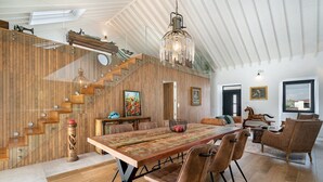 Une salle à manger spacieuse avec une longue table en bois, des chaises modernes et un lustre.