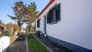 Un sendero estrecho que lleva a un edificio blanco con contraventanas verdes y tejado de tejas rojas.