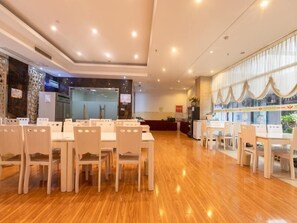 A hotel dining area with multiple tables and chairs, a kitchen area, and a reception desk. - Greentree Alliance Nanjing Yuhuatai District Nanjing South Station Hotel (Nanjing)
