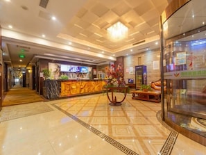 A hotel lobby with a reception desk, a chandelier, a patterned floor, and a glass display case. - Greentree Alliance Nanjing Yuhuatai District Nanjing South Station Hotel (Nanjing)