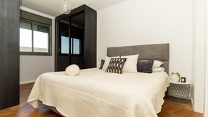 Un dormitorio con una cama grande, un armario, una mesita de noche y una ventana.