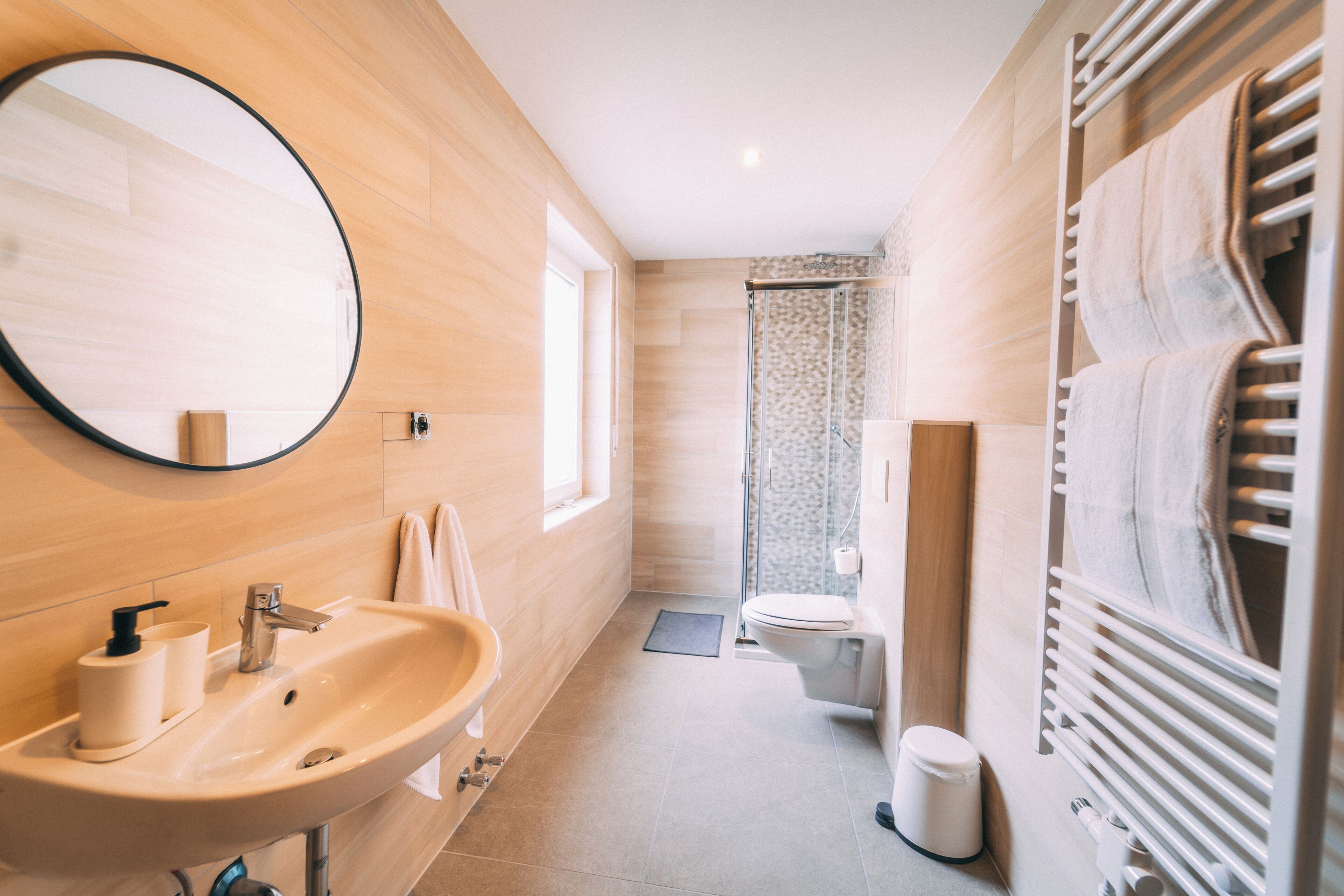 A modern bathroom with a sink, mirror, toilet, shower, and towel rack.