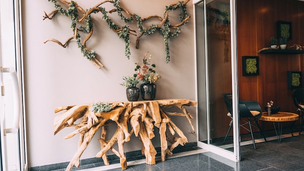 A lobby with a wooden art installation, a glass door, and a seating area with chairs and a small round table. - Premium Apartments Koblenz  (Koblenz)