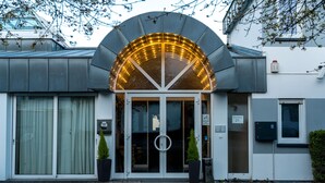 A hotel entrance with a glass door, a circular logo, and two potted plants. - Premium Apartments Koblenz  (Koblenz)