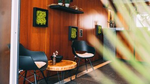 A reception area with wooden panel walls, black chairs, a round wooden table, and framed greenery on shelves. - Premium Apartments Koblenz  (Koblenz)