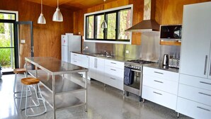 A modern kitchen with stainless steel appliances, a large window, and wooden walls.