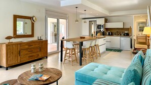 A modern kitchen with a central island, white cabinetry, and a dining area with bar stools.