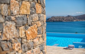 A stone wall, a swimming pool, and a view of the sea and mountains. - 6 bedrooms villa next to the beach  sleeps 12 (Plaka)
