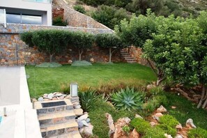 Une maison moderne avec une façade en pierre, une pelouse bien entretenue et une variété de plantes.
