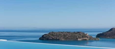 A clear view of a large, calm swimming pool with a rocky island in the center.