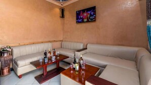 A room with a beige sofa, a wooden coffee table, and a television mounted on the wall. - Haber Motel  (Entebbe)