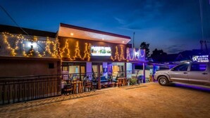 A hotel with a paved outdoor area, a car parked in front, and a sign indicating it is the Chaber Motel. - Haber Motel  (Entebbe)