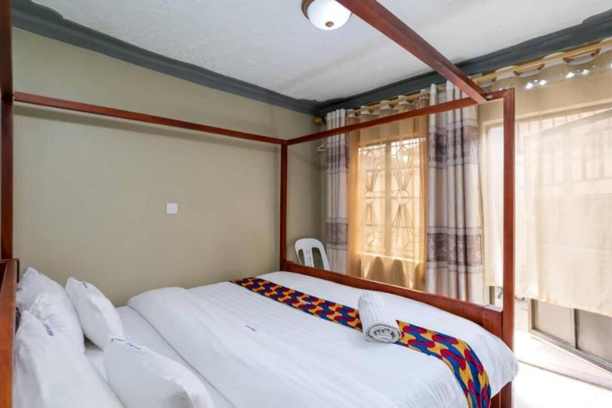 A bedroom with a bed, a chair, and a window with curtains.