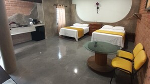 A hotel room with two beds, a dining table, chairs, a kitchen area, and a ceiling fan. - Bungalow loft with large garden and rural area close to all amenities (Puerto Vallarta)