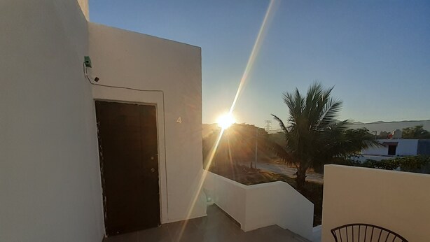A balcony with a door, a chair, and a view of the sunset. - Bungalow loft with large garden and rural area close to all amenities (Puerto Vallarta)