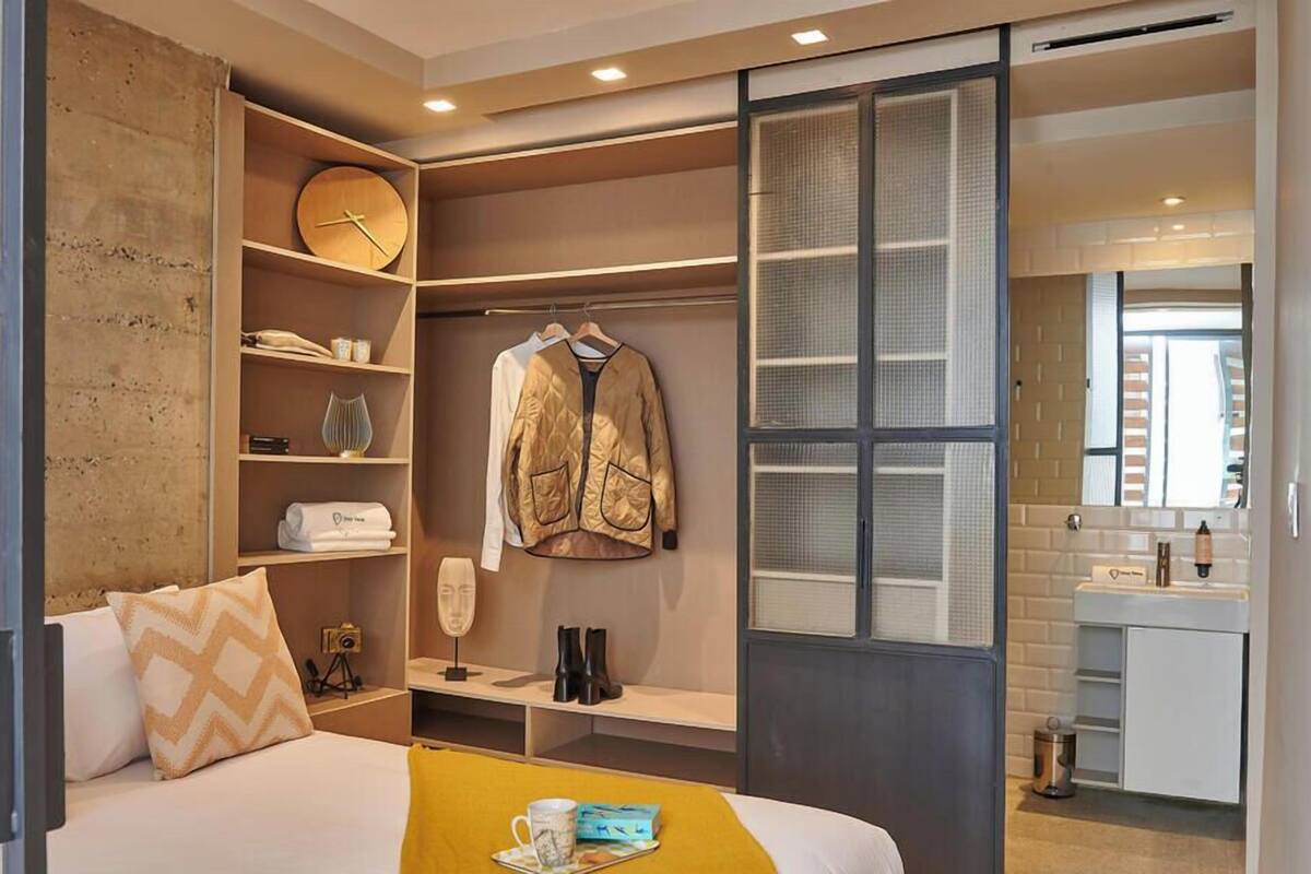 A hotel room with a bed, a wardrobe, a desk, and a bathroom.