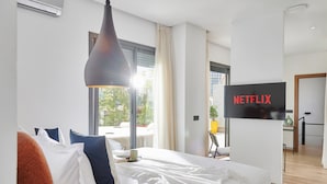 Habitación de hotel con cama, televisor, escritorio y ventana con cortinas.