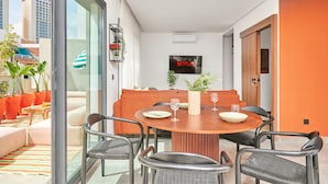 Un comedor moderno con una mesa redonda de madera, cuatro sillas y un televisor montado en la pared.