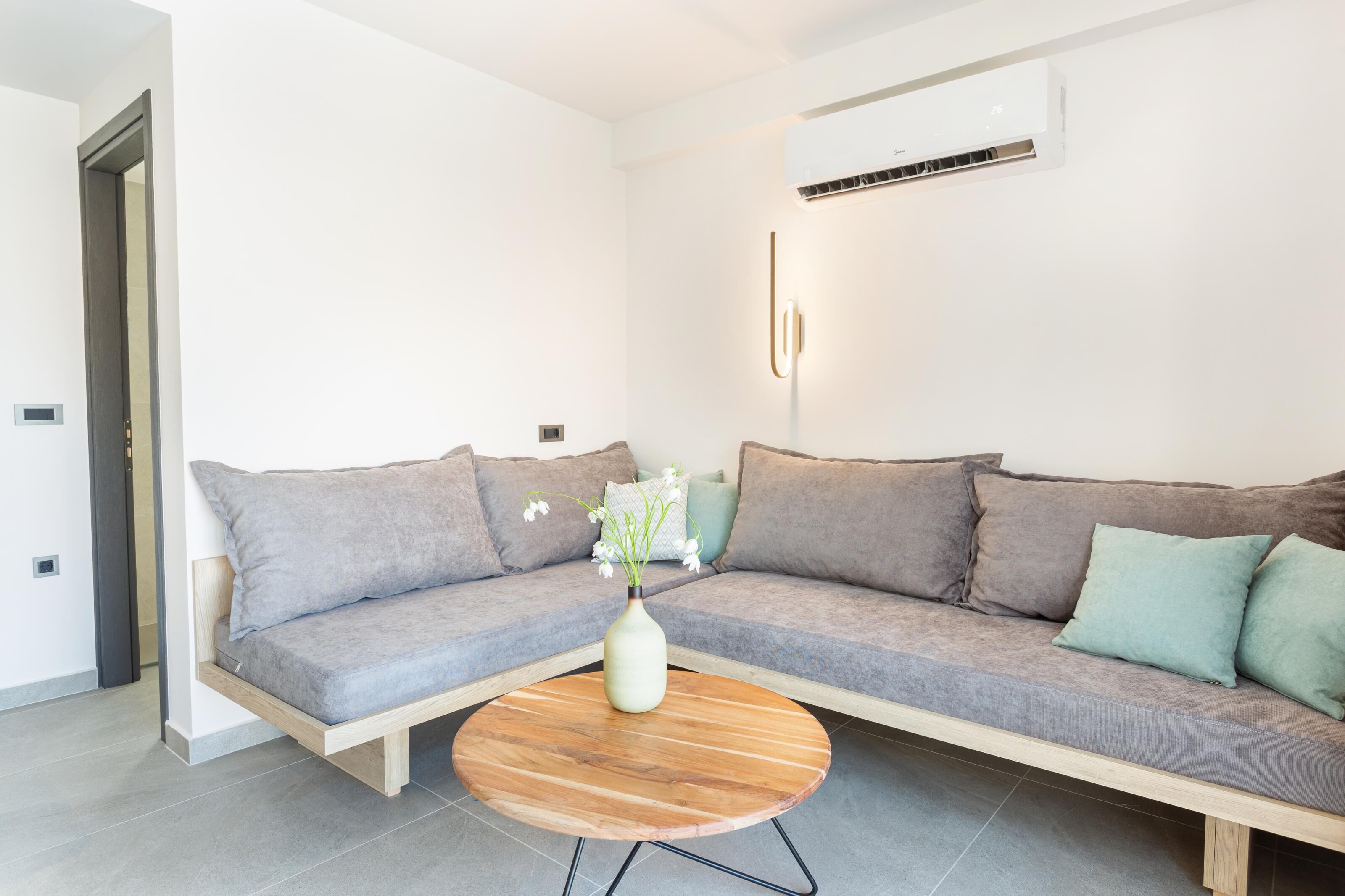 A modern living room with a grey sofa, a wooden coffee table, and a vase with flowers.