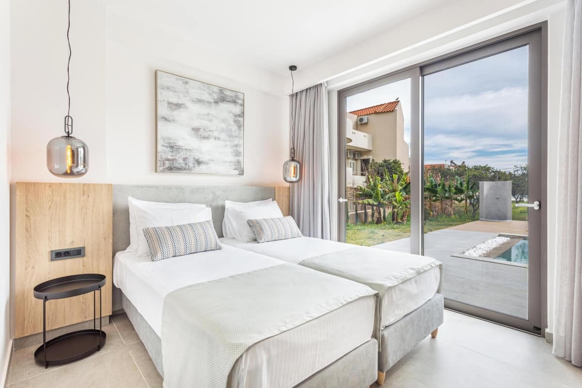 A hotel room with two beds, a large window, and a view of the outside.