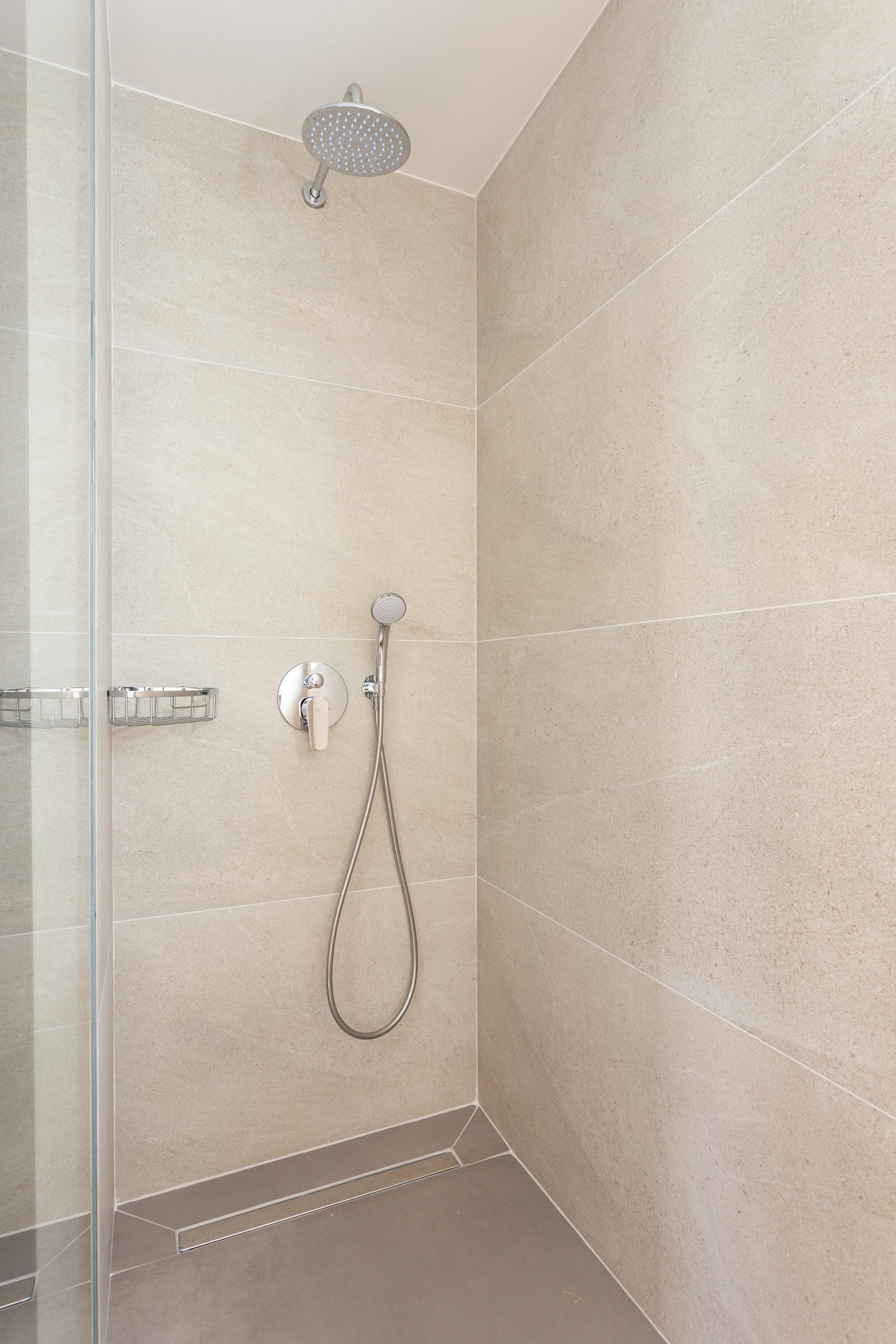 Ducha moderna con cabezal de ducha de mano y grifería empotrada.