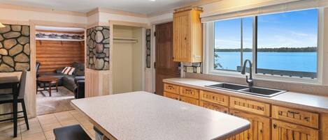 A kitchen with a stone countertop, wooden cabinets, and a view of a lake.