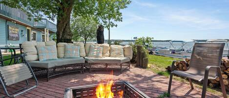 A patio with a fire pit, outdoor seating, and a view of the water.