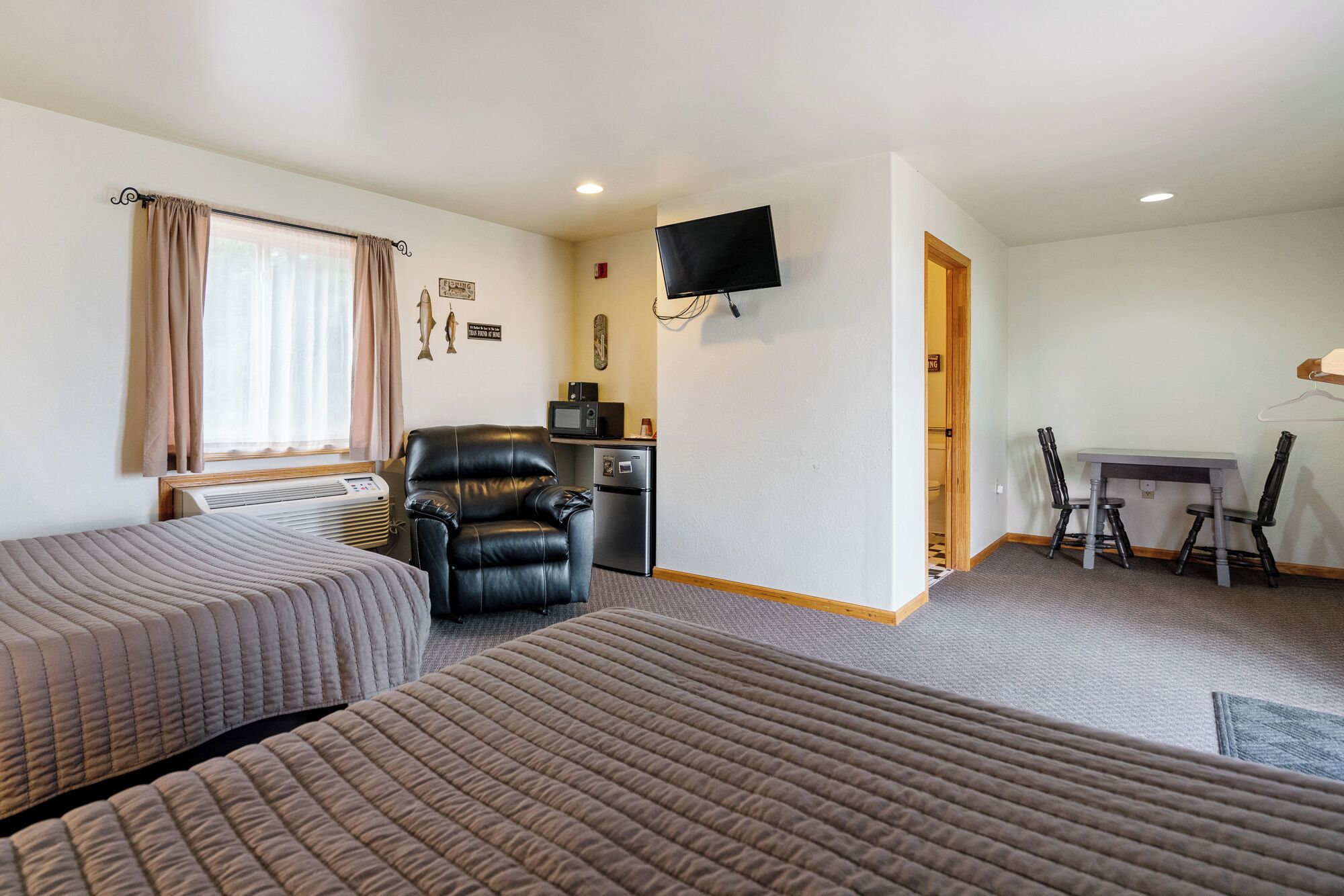 Une chambre d’hôtel avec deux lits, un bureau, une chaise, une télévision et une kitchenette.