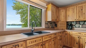 Una cocina con armarios de madera, encimera de granito, pileta doble y salpicadero de piedra.