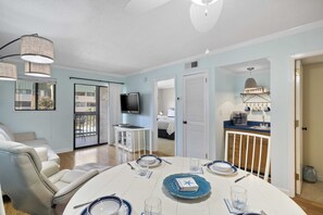 Relax in this spacious living room with a dining area, sofa, chair, flat-screen TV, and coffee maker.