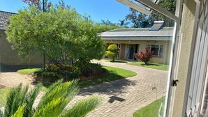 A house with a paved driveway leading to a garage, surrounded by well-maintained lawns and a variety of trees.