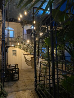 A covered outdoor area with a hammock, metal railing, and string lights.