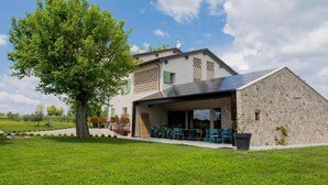 A modern house with a large garage, a tree in the front yard, and a clear sky. - Agriturismo Redó (Ponti sul Mincio)