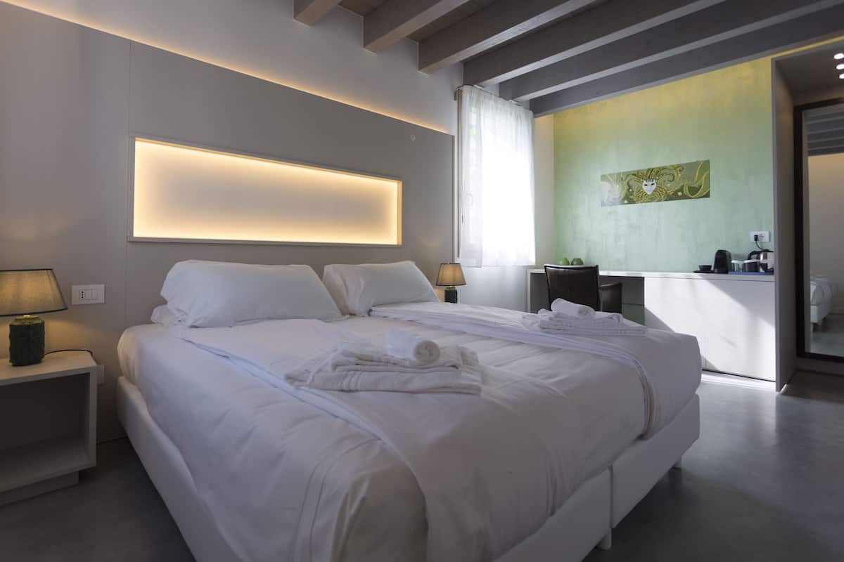 Une chambre d’hôtel moderne avec un grand lit, des lampes de chevet et vue sur la salle de bain.