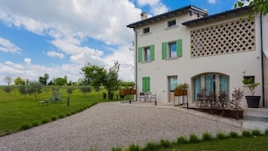 A two-story house with a gravel driveway, outdoor seating area, and a garden. - Agriturismo Redó (Ponti sul Mincio)