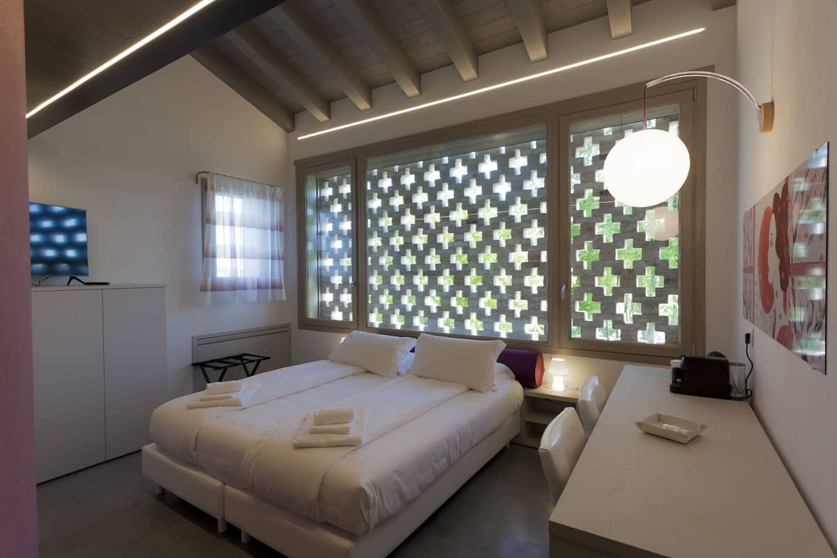 Une chambre d’hôtel moderne avec un grand lit, un bureau et une fenêtre dotée de vitres décorées.