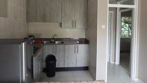 A kitchen with wooden cabinets, a stainless steel sink, and a trash bin.
