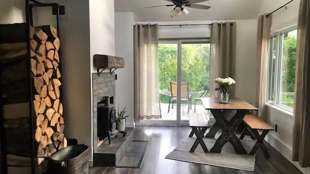 Een moderne woonkamer met een open haard, een eethoek met een tafel en stoelen, en uitzicht op de natuur via een schuifpui.