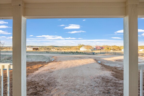A view from a covered porch with a dirt ground and a clear sky. - Private Hot Tub - Fireplace - 4 min. to downtown - Wildlife (Fredericksburg)