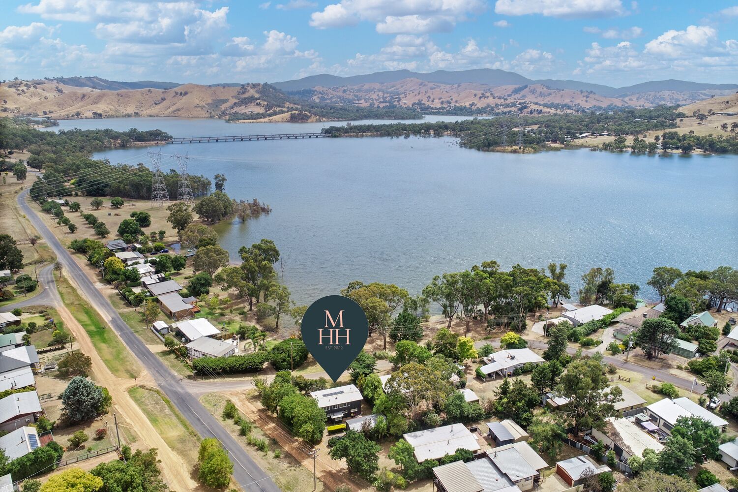 A residential area with houses near a large body of water, surrounded by hills.