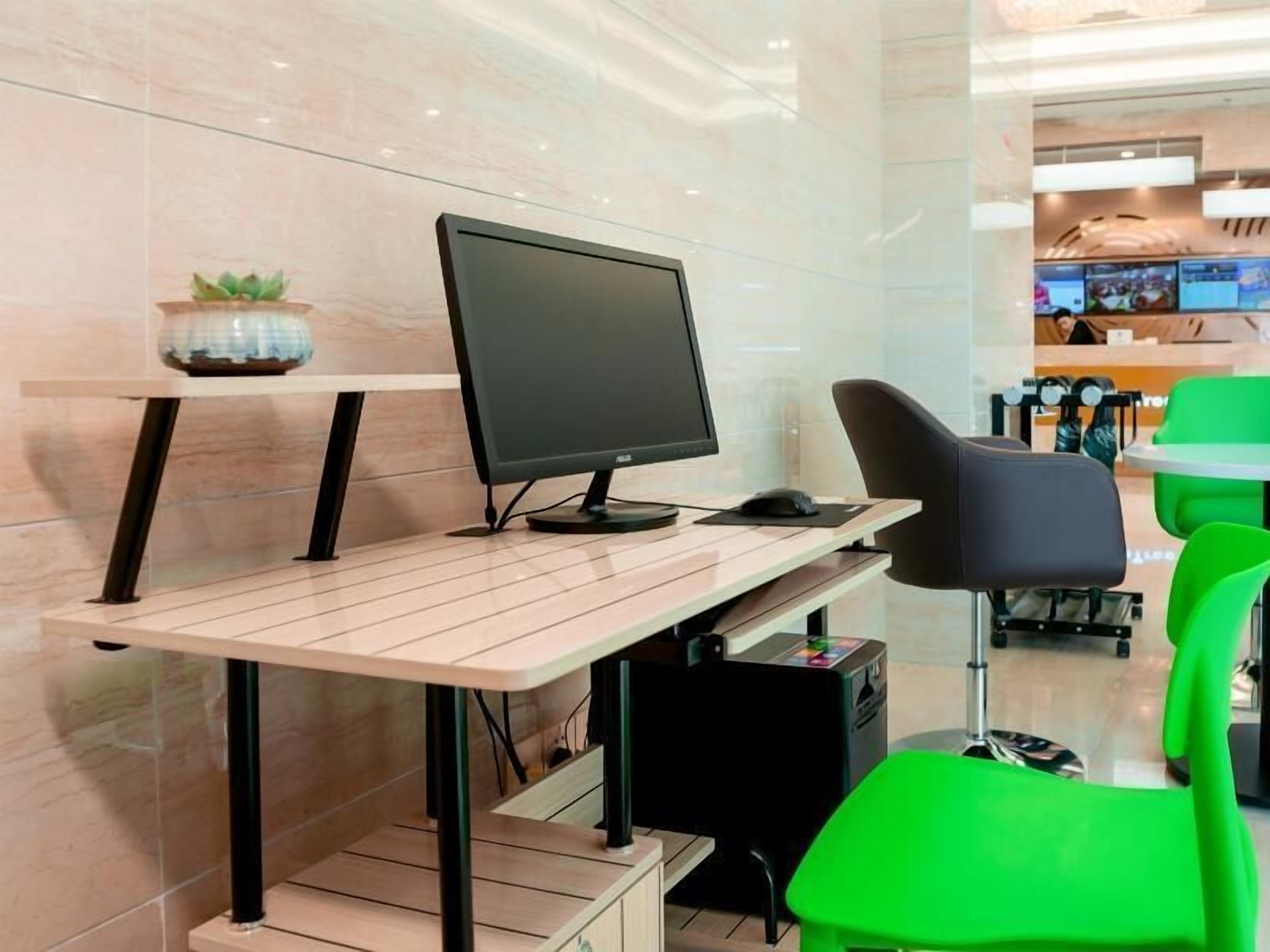Un espacio de oficina moderno con un escritorio, computadora y sillas verdes.