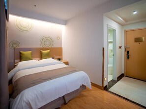 A modern hotel room with a large bed, a nightstand, a wall-mounted light, and a door with a keypad lock. - Greentree Inn Jiangsu Suzhou Zhangjiagang Tangshi Town Yangzi Road Express Hotel (Suzhou)