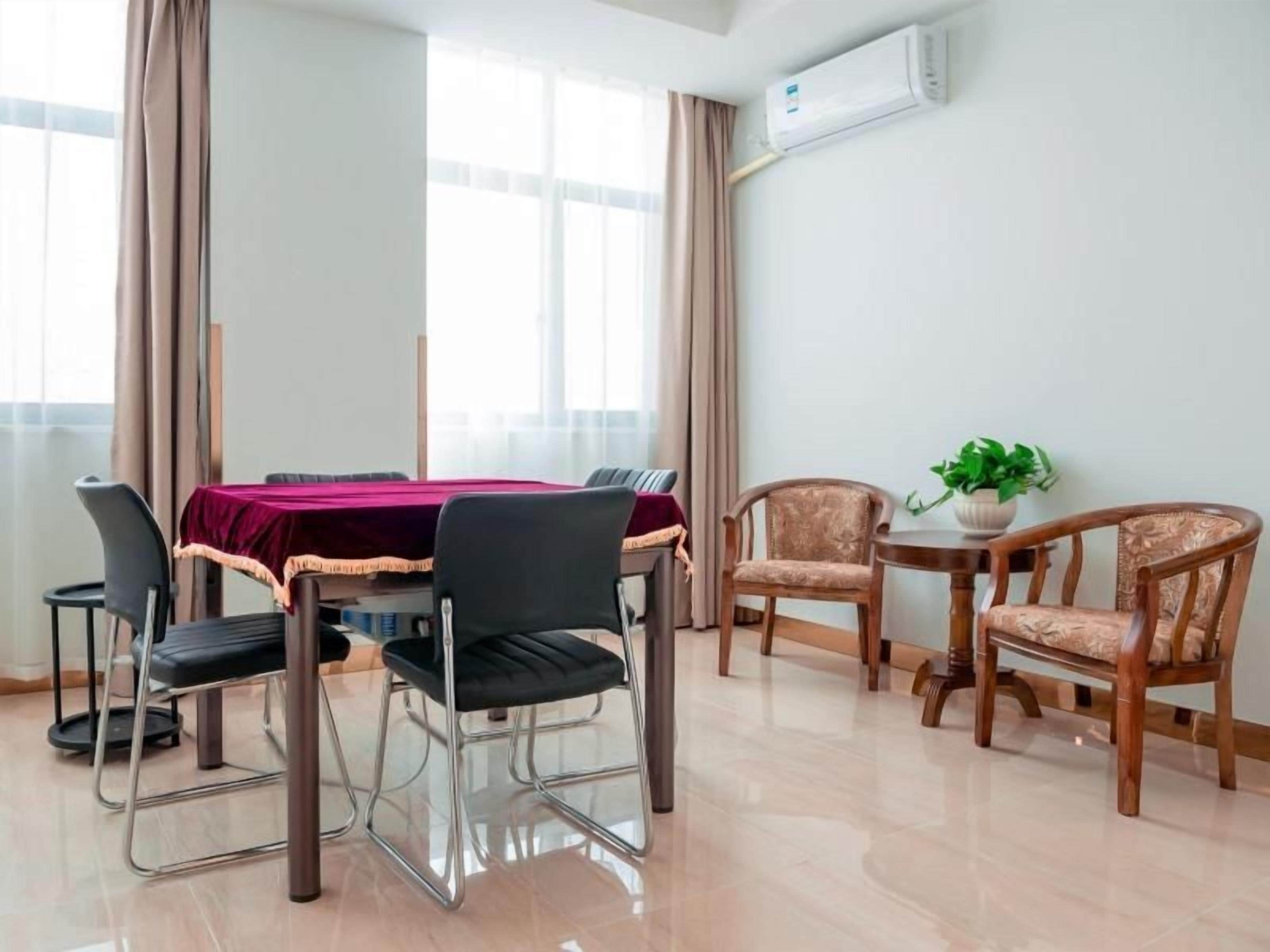 Un comedor con una mesa, sillas, una planta en maceta y un equipo de aire acondicionado en la pared.