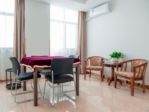 A dining area with a table and chairs, a potted plant, and an air conditioning unit on the wall. - Greentree Inn Jiangsu Suzhou Zhangjiagang Tangshi Town Yangzi Road Express Hotel (Suzhou)